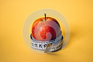 Healthy lifestyle concept. Red apple with measuring tape.