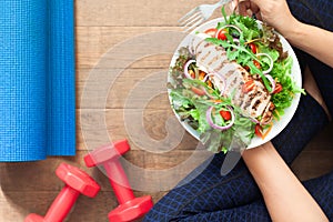 Healthy lifestyle concept. Top view sporty woman eating salad dish