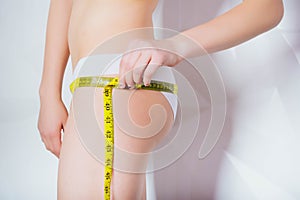 Healthy lifestyle concept - woman measures her waistline with a measuring tape in close-up.Sport girl measuring waist with yellow