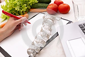 Healthy lifestyle concept. Writing weight loss plan with fresh vegetable diet and fitness