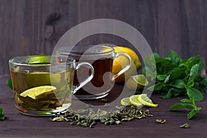 Healthy lifestyle. cups of green and black tea with lemon and leaves of green mint on wooden background. cups of green and black t