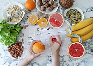 Young woman writing a diet plan. Fresh products set top view