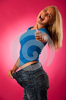 healthy lifestyle - fit blond woman with too big trousers gesturing weight loose
