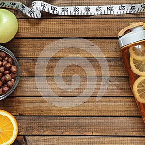 Healthy lifestyle; fitness bottle; fruits oranges; apples and bananas; hazelnuts and peanuts; orange juice and measuring tape. T