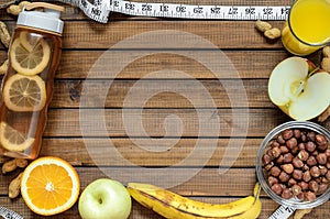 Healthy lifestyle; fitness bottle; fruits oranges; apples and bananas; hazelnuts and peanuts; orange juice and measuring tape. T