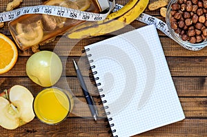 Healthy lifestyle; fitness bottle; fruits oranges; apples and bananas; hazelnuts and peanuts; orange juice, a pen and a notebook