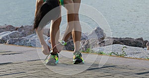 Healthy lifestyle fitness woman runner tying shoelace before running on sunny seaside