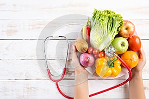 Healthy lifestyle, food and nutrition concept. Close up doctor woman hand holding plate of fresh vegetables and fruits with