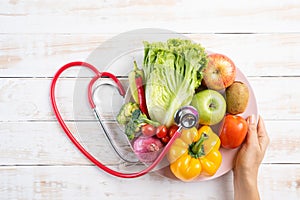 Healthy lifestyle, food and nutrition concept. Close up doctor woman hand holding plate of fresh vegetables and fruits with