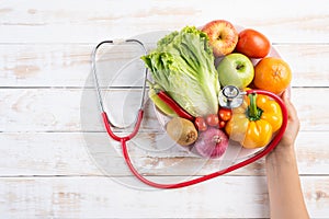 Healthy lifestyle, food and nutrition concept. Close up doctor woman hand holding plate of fresh vegetables and fruits with