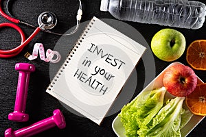 Healthy lifestyle, food and sport concept. Top view of Stethoscope measuring tape pink dumbbell, sport water bottles, fruit and