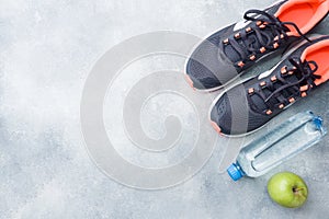 Healthy lifestyle, food and water, athlete`s equipment on grey background. Flat lay. Top view with copy space