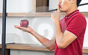 Healthy lifestyle and freshness concept. Smart, young and healthy Asian man eating apple in the loft style kitchen room