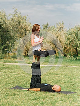 Healthy lifestyle modern activity. Young couple doing acro bird yoga pose.