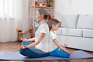 Healthy Lifestyle. Mother and daughter in sportswear doing yoga sitting back to back on mat hands in prayer mediating