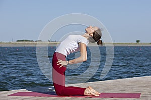 Healthy lifestyle in nature,Woman doing yoga exercise on mat in park near lake