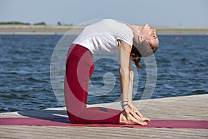 Healthy lifestyle in nature,Woman doing yoga exercise on mat in park near lake