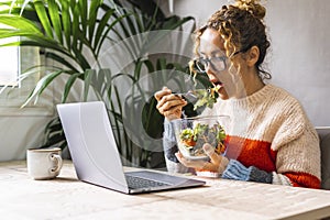 Healthy lifestyle people and business busy activity. One woman eating green fresh salads in front of a computer at the table in