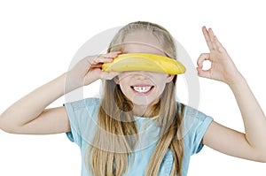 Healthy lifestyle people. Funny image of little girl holding fresh banana showing like sign.