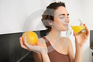 Healthy lifestyle and sport. Beautiful smiling woman, drinking fresh orange juice and holding fruit in her hand