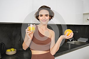 Healthy lifestyle and sport. Beautiful smiling woman, drinking fresh orange juice and holding fruit in her hand