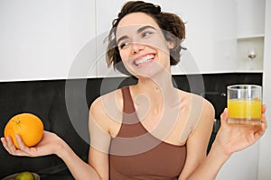 Healthy lifestyle and sport. Beautiful smiling woman, drinking fresh orange juice and holding fruit in her hand