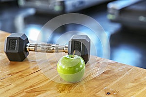 Healthy lifestyle sport. Dumbbells, and healthy food on wooden. green apple in the gym or sport club. Healthy lifestyle sport