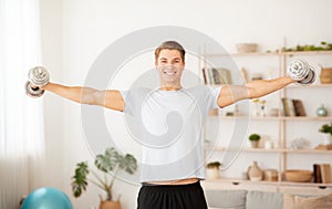 Healthy lifestyle and strength training. Strong man raises dumbbells in interior