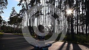 Healthy lifestyle. Woman drink water in lotus pose on natute background. Forest, sun rays trees. Drink pure water on