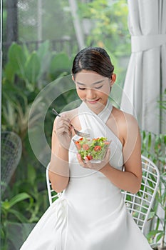 Healthy lifestyle woman eating salad smiling happy indoors on beautiful day