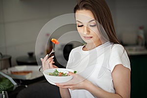 Healthy lifestyle woman eating salad smiling happy in light kitchen