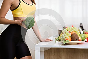 Healthy lifestyle. Woman holding broccoli and cooking after exercising