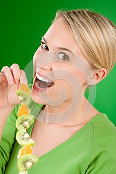 Healthy lifestyle - woman kiwi and orange on stick