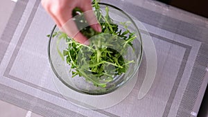 Healthy lifestyle - Woman pouring arugula into glass bowl