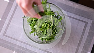 Healthy lifestyle - Woman pouring arugula into glass bowl