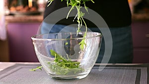 Healthy lifestyle - Woman pouring arugula into glass bowl