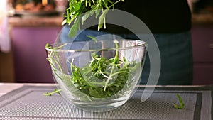 Healthy lifestyle - Woman pouring arugula into glass bowl