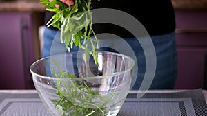 Healthy lifestyle - Woman pouring arugula into glass bowl