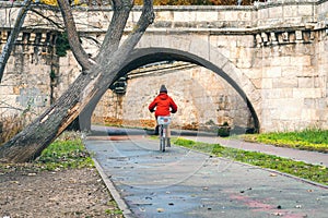 Healthy lifestyle, woman with red jacket riding the bike in the park during autumn