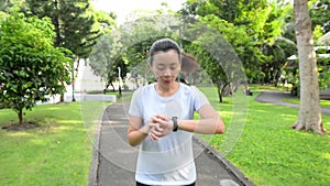 Healthy lifestyle woman in sportswear running and watching her watch in the park at sunset