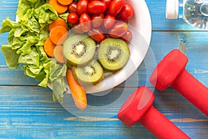 Healthy lifestyle for women diet with sport equipment, sneakers, vegetable fresh and bottle of water on wooden.