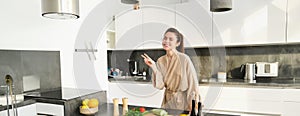 Healthy lifestyle. Young woman in bathrobe preparing food, chopping vegetables, cooking dinner on kitchen counter