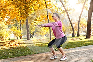 Healthy Lifestyle. Young woman doing squat outdoors autumn season smiling happy