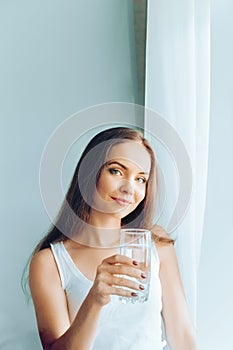 Healthy lifestyle.Young woman drinking from a glass of  fresh water. Healthcare. Drinks. Portrait of happy smiling female model ho