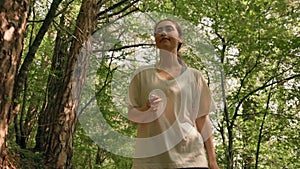 Healthy lifestyle. A young woman is engaged in trekking in a summer forest, listening to music on an MP3 player. Bottom