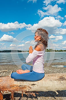 Healthy lifestyle young woman meditate on fresh air on river beach  sunny summer day