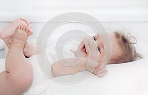 Healthy little happy baby boy lying on soft white pillow