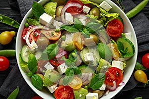 Healthy low calories salad with lettuce, heirloom tomatoes, avocado, feta cheese, red onion, cucumber, sweet peas