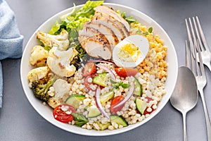 Healthy lunch bowl with grilled chicken, roasted vegetables, fresh lettuce, cooked lentils, salad and boiled egg