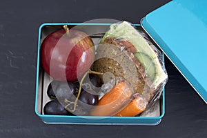 Healthy lunch box, cheese sandwich, apple, carrots and grapes